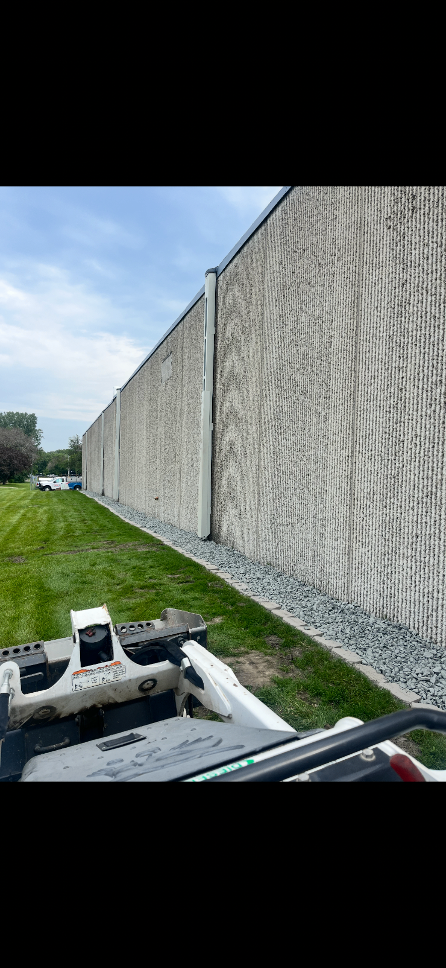 Decorative river rock drainage strip installed along a commercial wall
